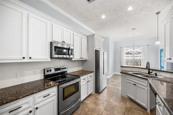 a kitchen with granite countertop a sink stainless steel appliances and cabinets
