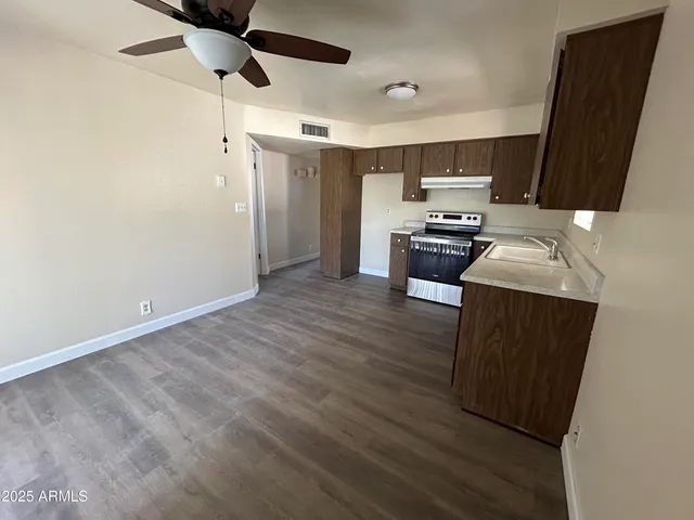 a kitchen with stainless steel appliances a stove a refrigerator a sink a microwave oven with wooden floor and cabinets