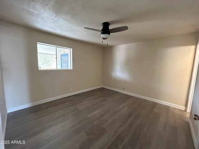 an empty room with wooden floor ceiling fan and windows