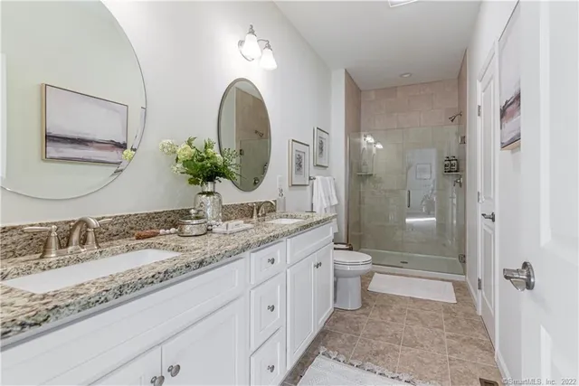a bathroom with a granite countertop sink a toilet and shower