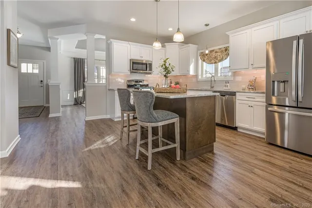 a kitchen with stainless steel appliances kitchen island granite countertop a table chairs refrigerator sink and cabinets