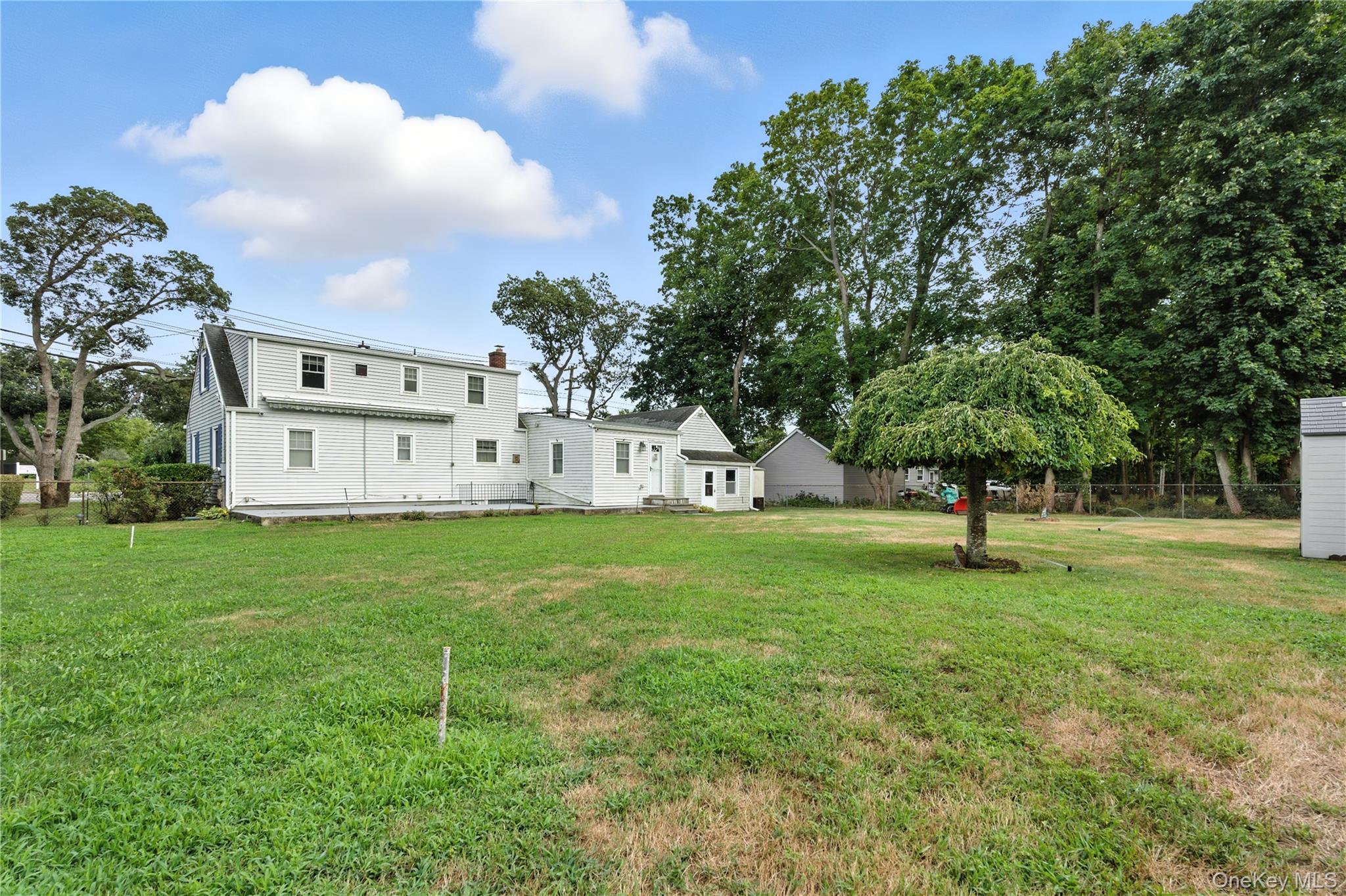 1547 Walt Whitman Road Melville, NY 11747 - Photo 22 of 25 a view of a white house with a big yard and a large tree