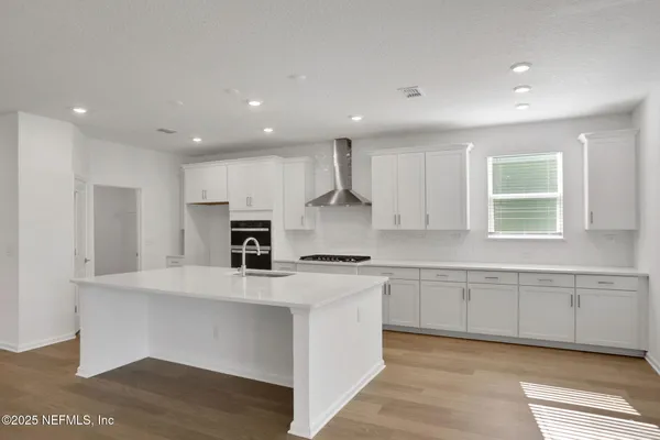 a view of an empty room with wooden floor and windows