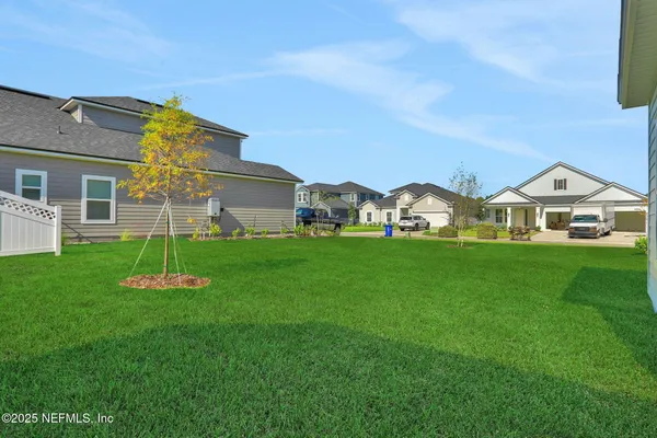a view of a white house with a big yard and large trees