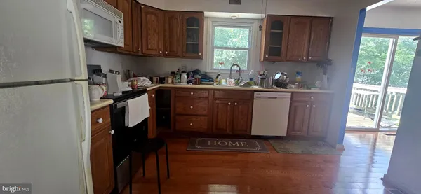 a kitchen with stainless steel appliances granite countertop a refrigerator sink and wooden cabinets
