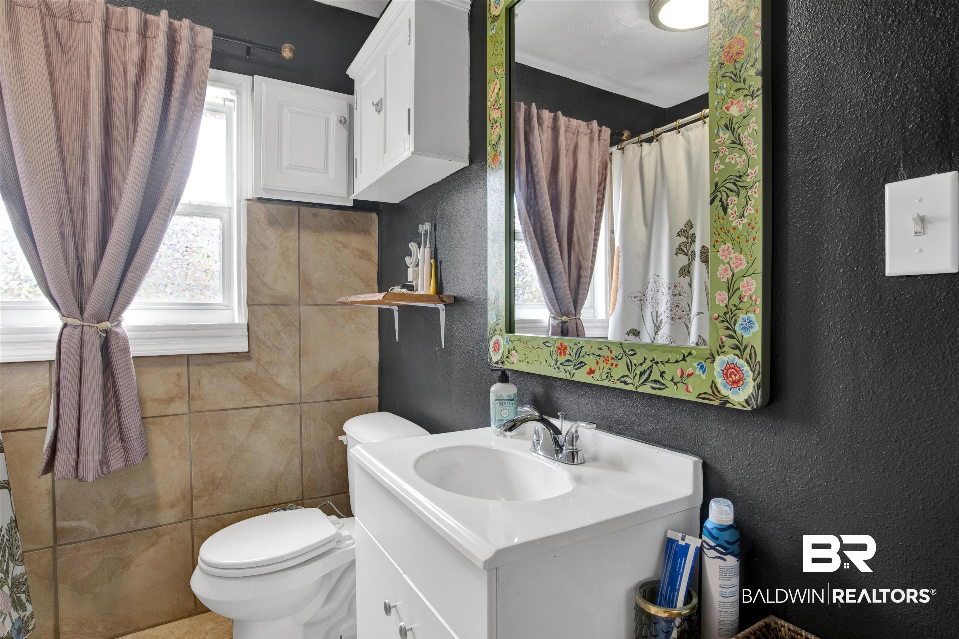 1100 North Pine Street Foley, AL 36535 - Photo 14 of 30 Bathroom featuring a white vanity with integrated sink, chrome faucet, and white overhead cabinetry