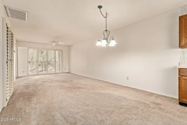 a view of an empty room with chandelier and a window