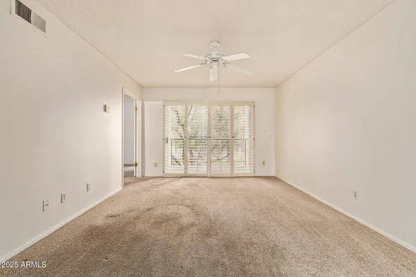 an empty room with a large window and a ceiling fan