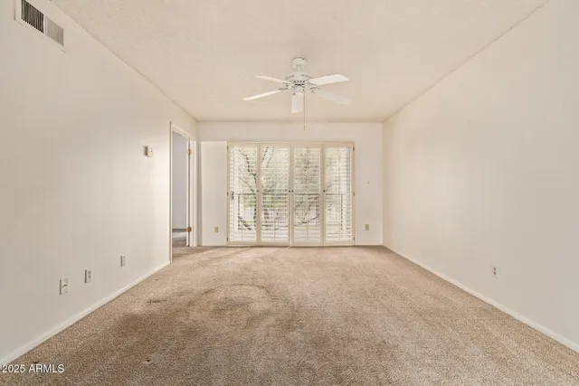 an empty room with a large window and a ceiling fan