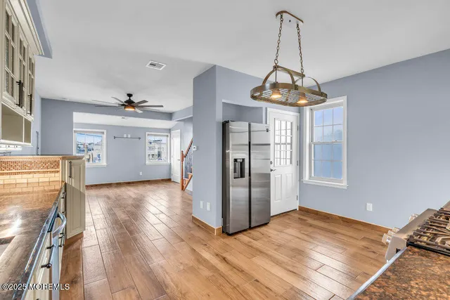 an empty room with wooden floor chandelier and windows