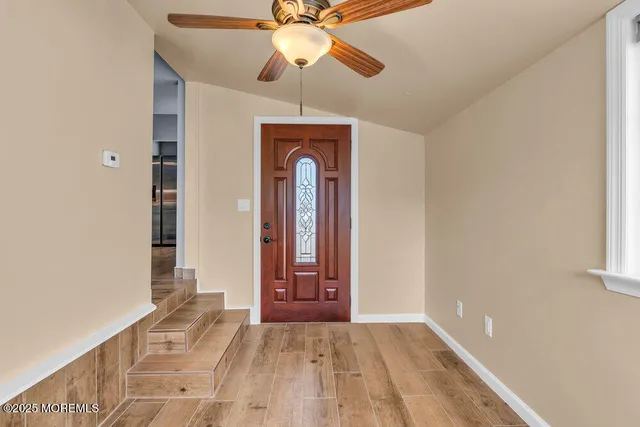 a view of a room with wooden floor and a ceiling fan