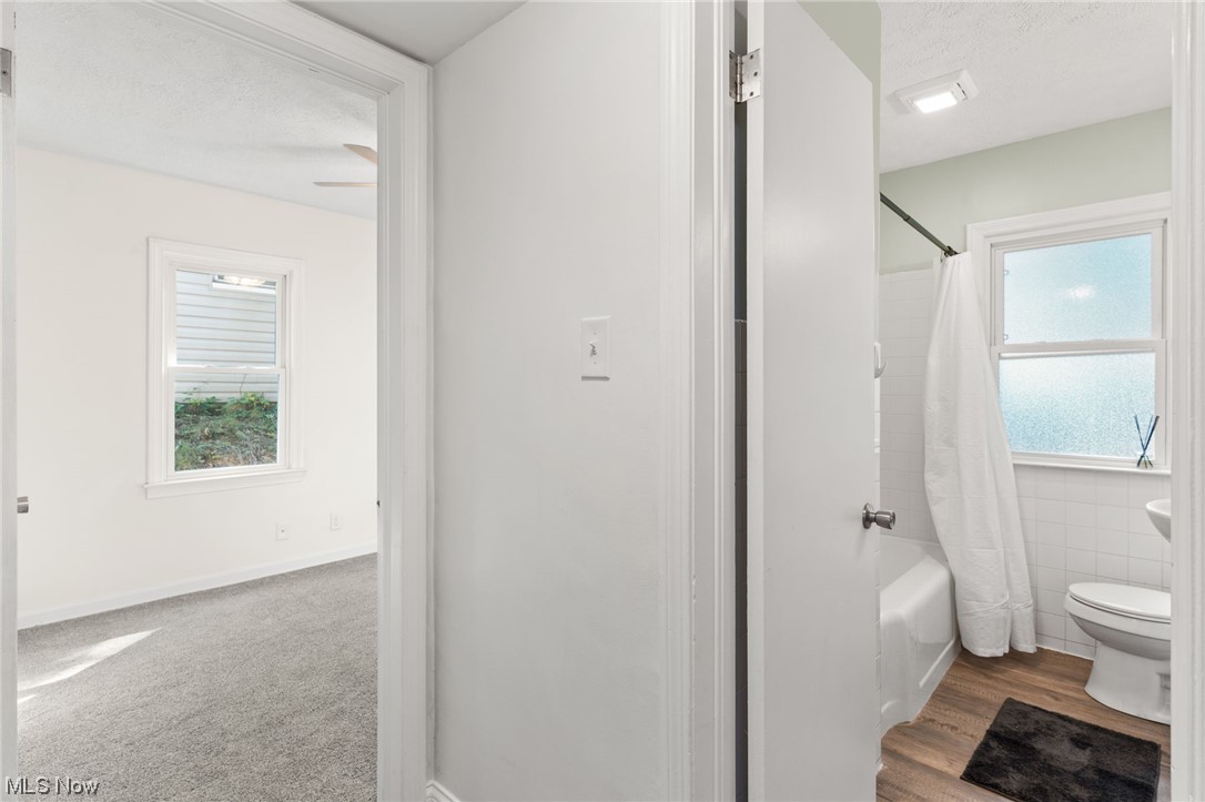 898 Reed Avenue Akron, OH 44306 - Photo 17 of 26 Bathroom featuring a textured ceiling, shower / tub combo with curtain, a wealth of natural light, tile walls, and light hardwood floors