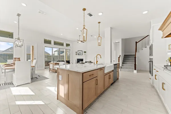 a large kitchen with kitchen island a stove a sink a chimney and living room view