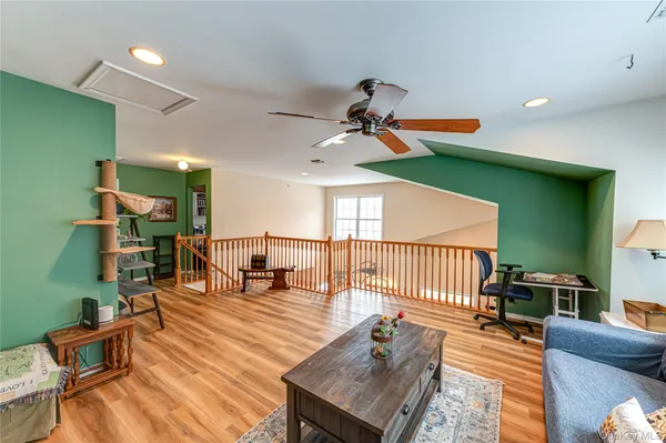 a living room with furniture a wooden floor and a ceiling fan