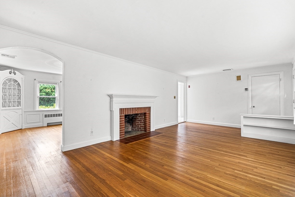 6 Old Colony Road Arlington, MA 02474 - Photo 3 of 15 an empty room with wooden floor fireplace and windows