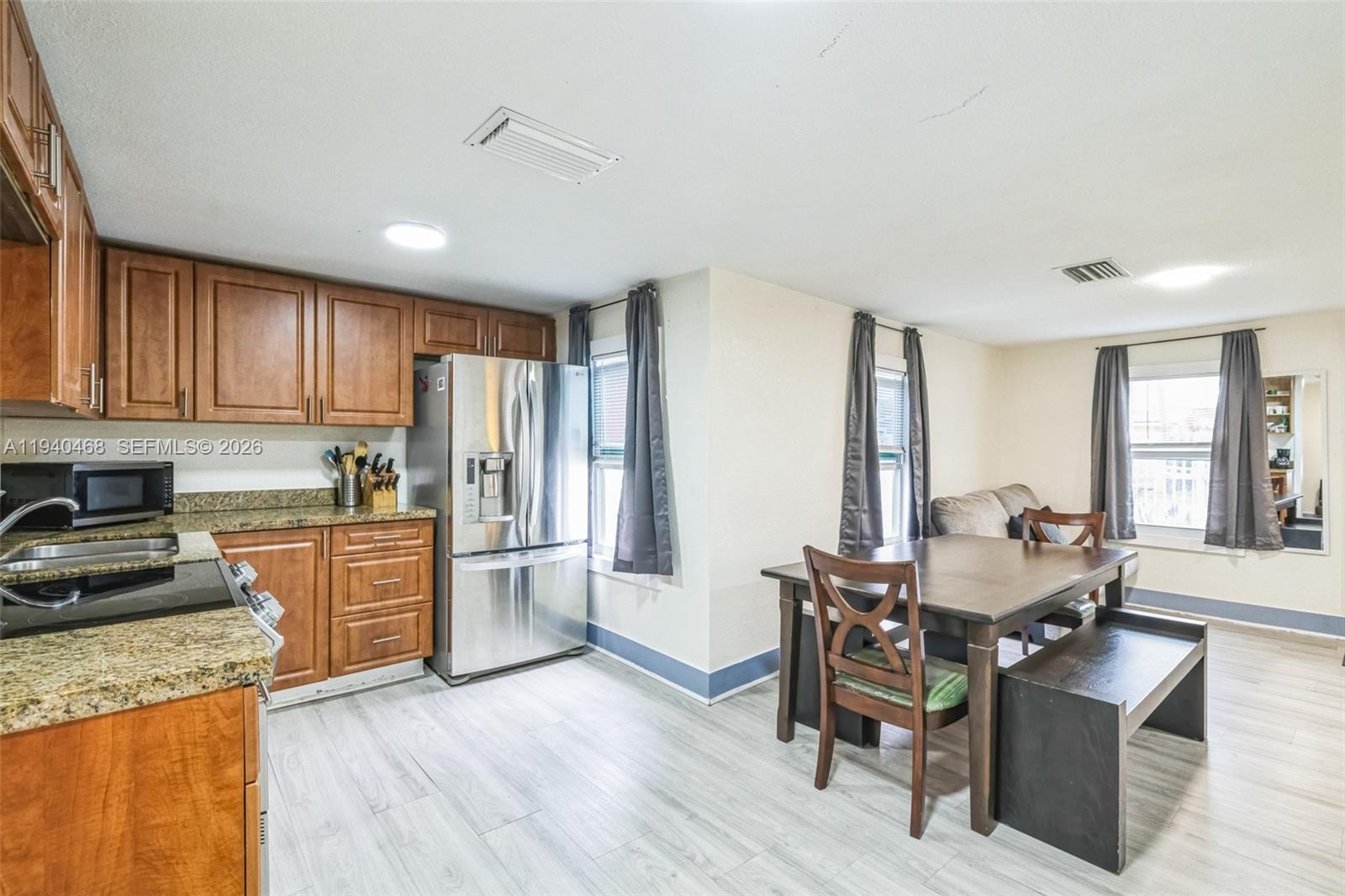 1296 Northwest 72nd Street Miami, FL 33147 - Photo 2 of 12 a kitchen with stainless steel appliances granite countertop a stove top oven a sink dishwasher a dining table and chairs with wooden floor