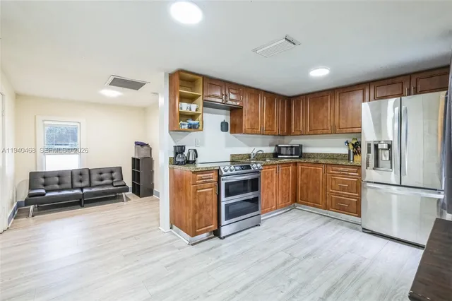 a kitchen with granite countertop wooden floors stainless steel appliances and a window