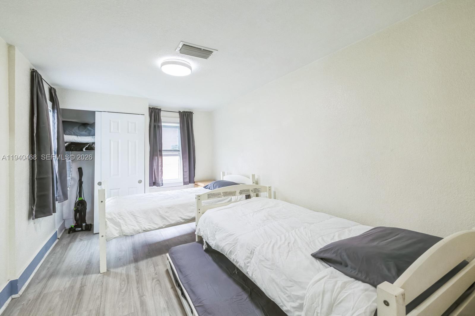 1296 Northwest 72nd Street Miami, FL 33147 - Photo 7 of 12 a spacious bedroom with a bed and a wooden floor