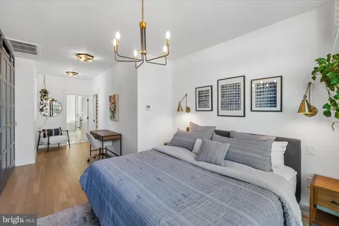 a bedroom with a bed a table and painting on the wall