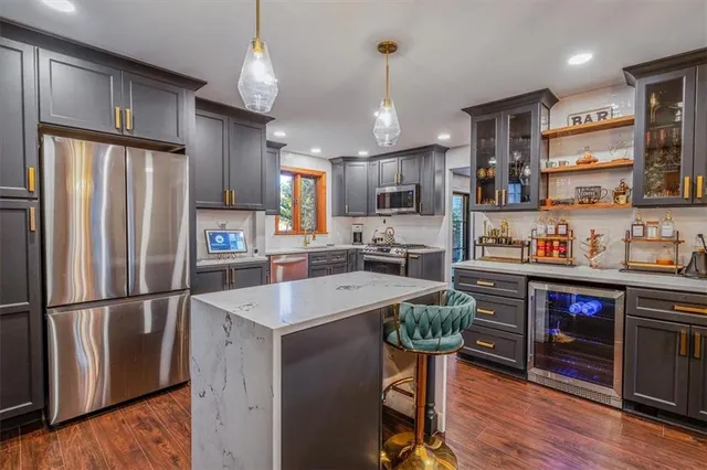 a kitchen with stainless steel appliances granite countertop a refrigerator a sink dishwasher a stove and a refrigerator with wooden floor