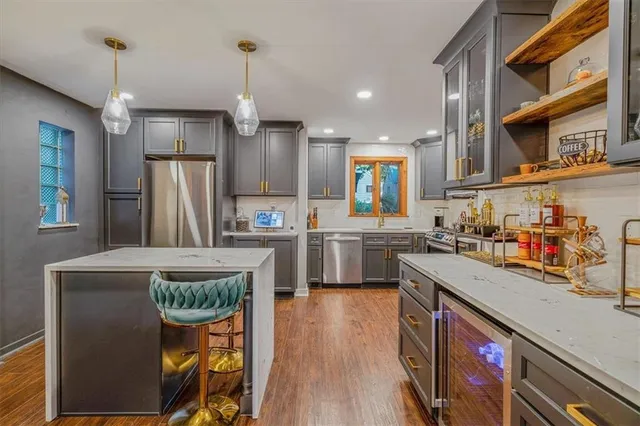 a kitchen with stainless steel appliances granite countertop a refrigerator a sink dishwasher a stove and white countertops with wooden floor