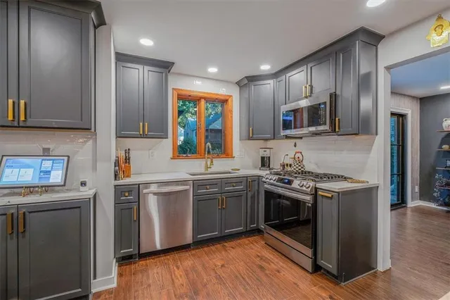 a kitchen with stainless steel appliances granite countertop a stove top oven a sink and a refrigerator