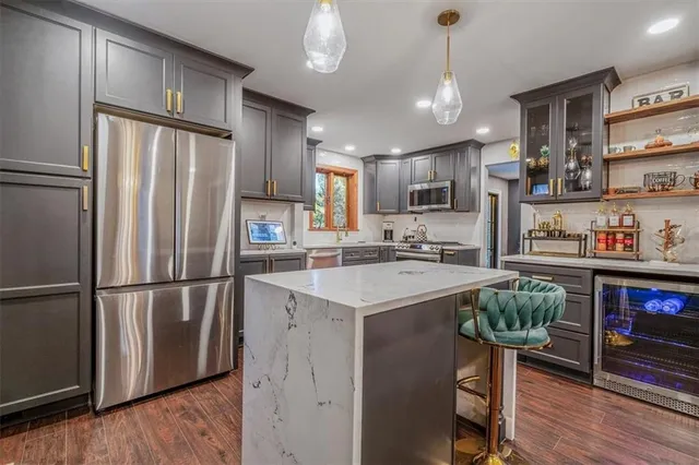 a kitchen with stainless steel appliances granite countertop a refrigerator a sink dishwasher a stove and a refrigerator with wooden floor