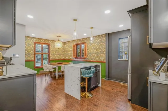 a kitchen with stainless steel appliances granite countertop a refrigerator a sink dishwasher a stove and a dining table with wooden floor