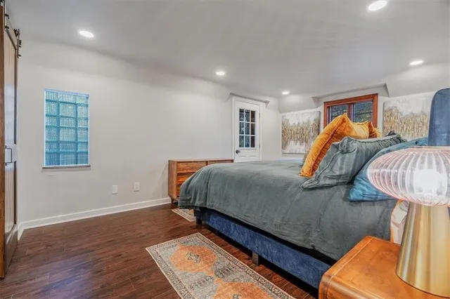 a bedroom with a bed a lamp and wooden floor