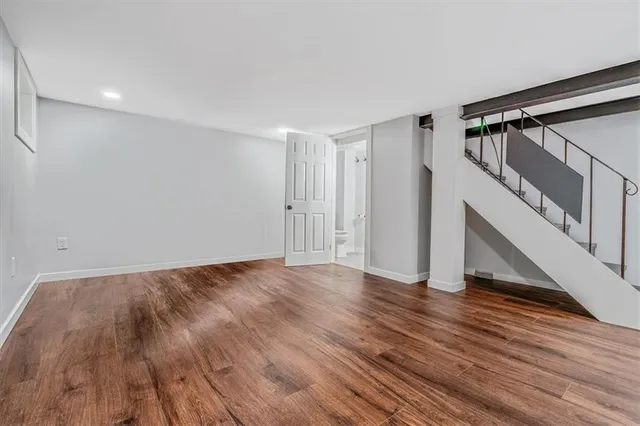 a view of an empty room with wooden floor and stairs