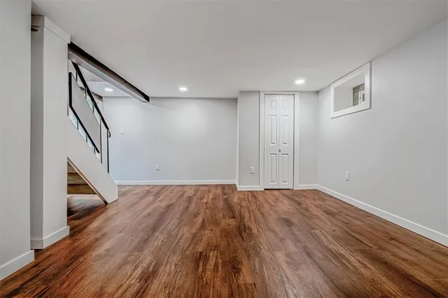 a view of an empty room with wooden floor and stairs