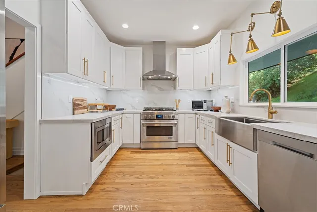 a kitchen with stainless steel appliances a white cabinets and a stove top oven
