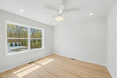 an empty room with wooden floor fan and windows