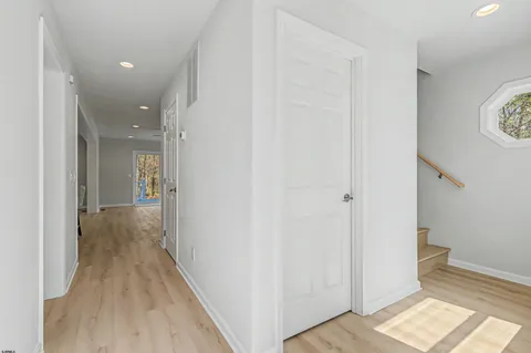 a view of a hallway with wooden floor and a bathroom