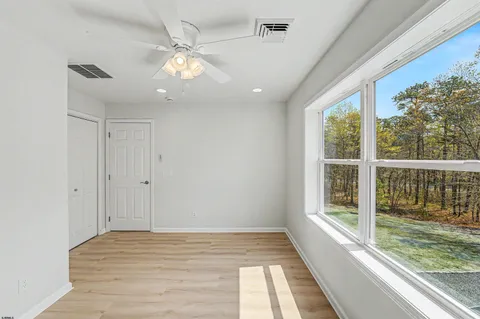 a view of empty room with wooden floor and fan