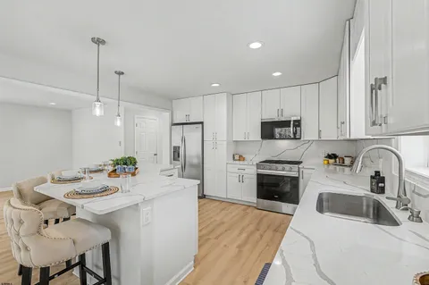 a kitchen with stainless steel appliances a sink a stove a refrigerator cabinets a dining table and chairs
