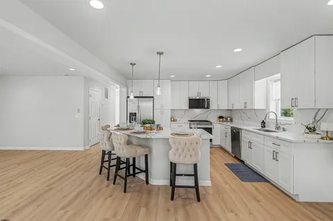 a kitchen with stainless steel appliances a dining table chairs sink and cabinets
