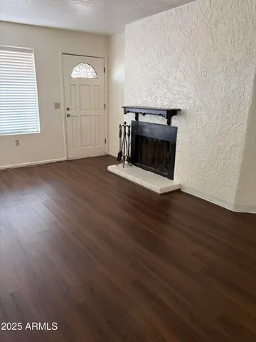 an empty room with wooden floor fireplace and windows