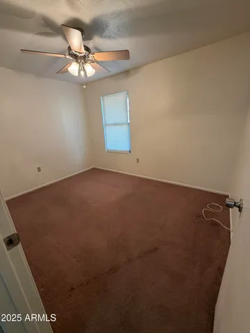 en empty room with a fan and a chandelier fan