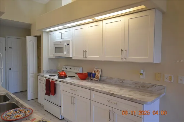 a kitchen with white cabinets and white appliances