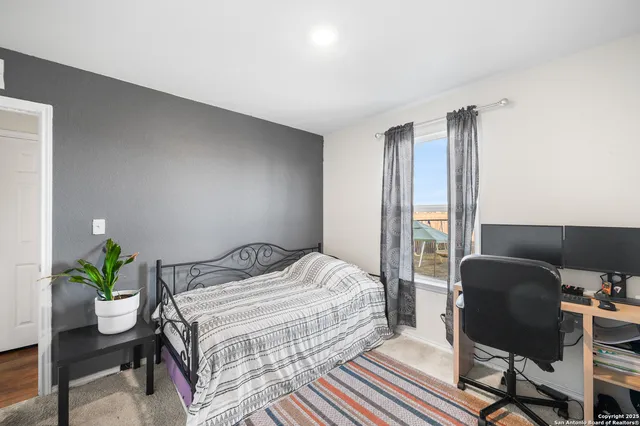 a bedroom with a bed table chair and a potted plant