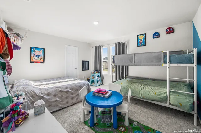 a bedroom with a bed a standing fan and a bookshelf