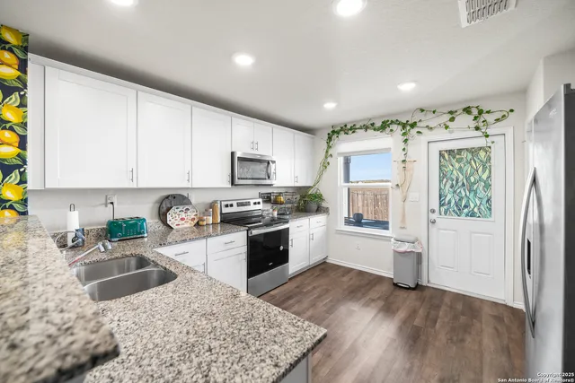 a kitchen with granite countertop a stove top oven a sink dishwasher and a refrigerator with wooden floor