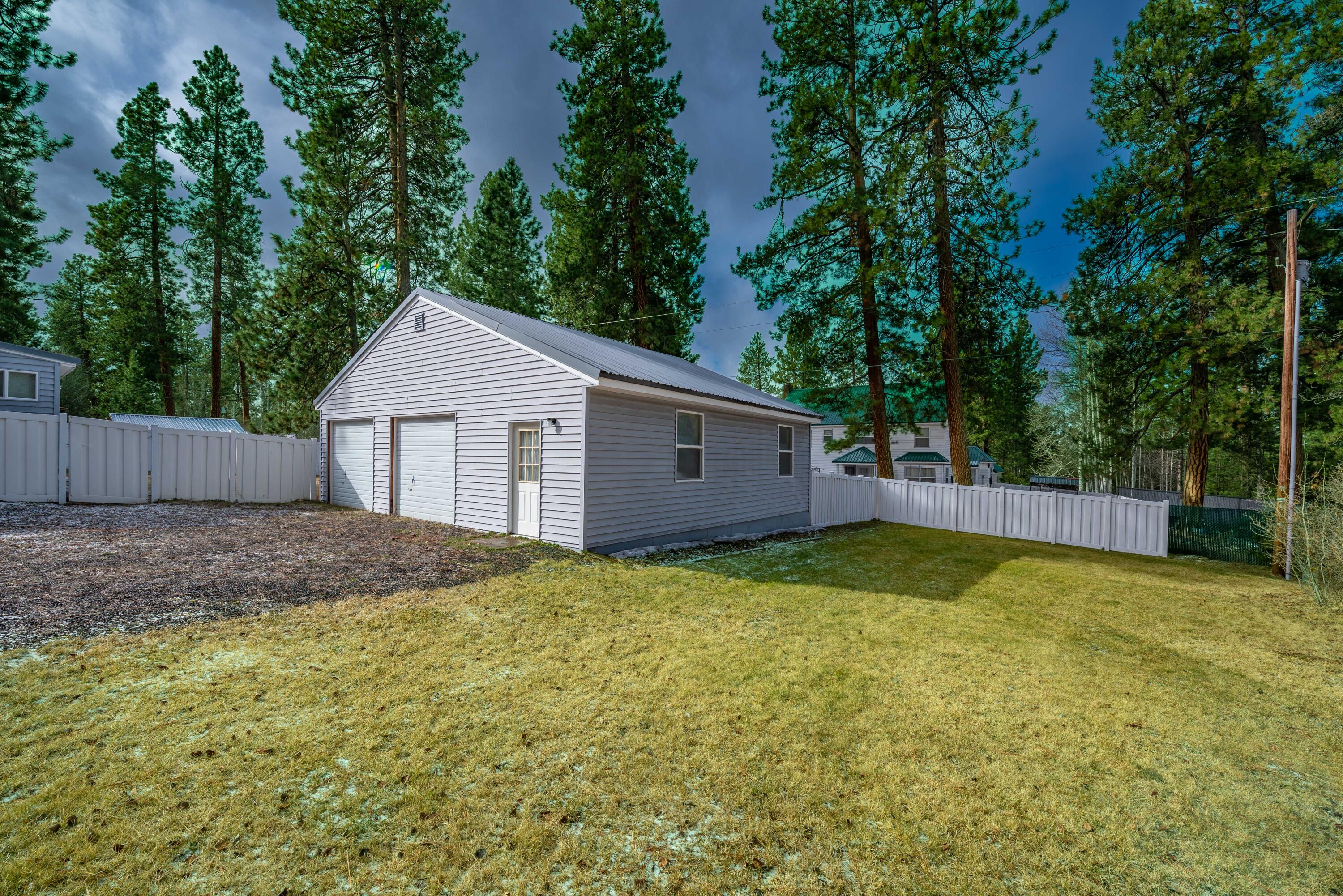 138722 Rhododendron Street Gilchrist, OR 97737 - Photo 35 of 36 a view of a yard in front of a house with large trees and wooden fence