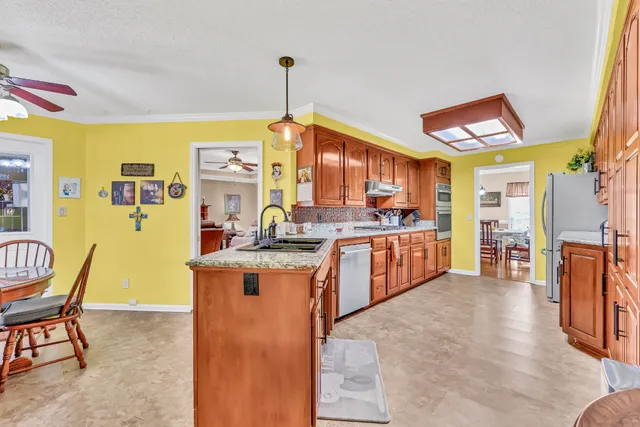 a kitchen with stainless steel appliances kitchen island granite countertop a table chairs in it and a wooden floor