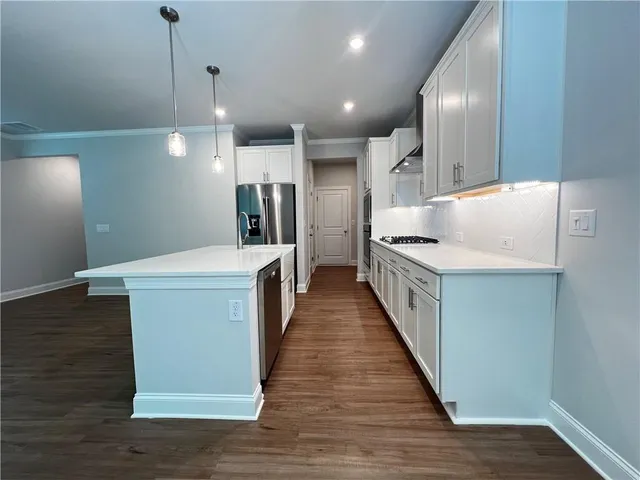 a kitchen with kitchen island a counter top space a sink and a refrigerator