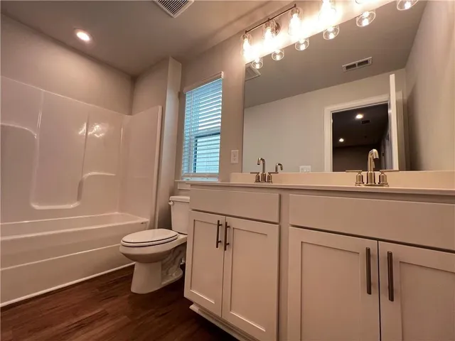 a bathroom with a double vanity sink a toilet a mirror and shower