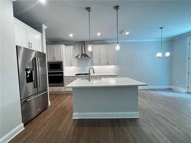 a kitchen with kitchen island a sink stainless steel appliances and wooden floor