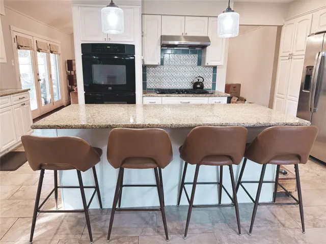 a kitchen with stainless steel appliances kitchen island granite countertop a table chairs in it and wooden floors