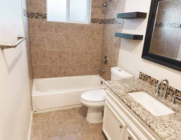 a bathroom with a granite countertop toilet a sink and bathtub